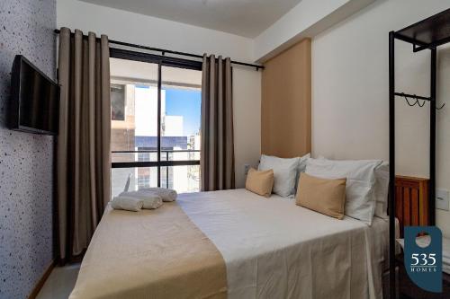 - une chambre avec un grand lit et une grande fenêtre dans l'établissement Mar & Conforto: Seu lar em Salvador, à Salvador