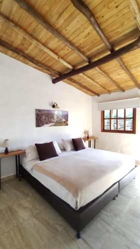 a large bed in a bedroom with a wooden ceiling at Hotel Boutique Santa Clara Mesa de los Santos in Los Santos