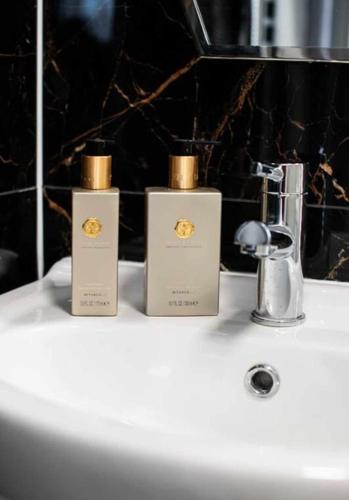 two bottles of soap sitting on a bathroom sink at Luxury ApArt Gallery Apartment 1 Near River & Free Parking in Bedford