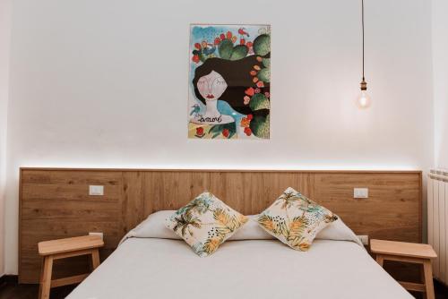 uma cama com duas almofadas e um quadro na parede em Terrae Hydrunti em Lecce