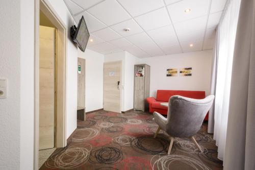 a waiting room with a chair and a red couch at Hotel Engelhorn in Leimen