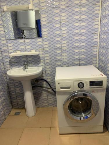 uma máquina de lavar roupa e um lavatório na casa de banho em Maison personnelle d'une chambre salon meublé em Cotonou