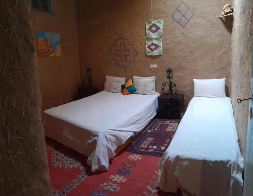 - 2 lits dans une chambre avec des draps blancs dans l'établissement Oasis travel, à Tazouka