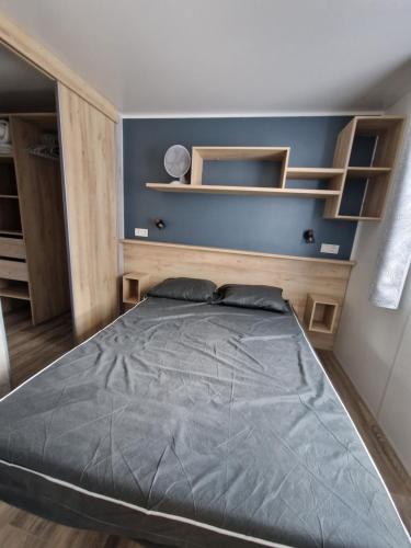 Un dormitorio con una cama grande con estantes de madera. en Louons ensemble, en Saint-Jean-de-Monts
