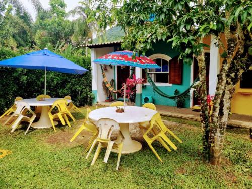 two tables and chairs with umbrellas in front of a house at Pousada_tres_amores in Itariri
