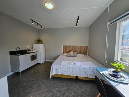 Schlafzimmer mit einem Bett, einem Kühlschrank und einem Tisch in der Unterkunft Residenz100 in Blumenau