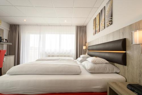 a bedroom with three beds with white pillows at Hotel Engelhorn in Leimen