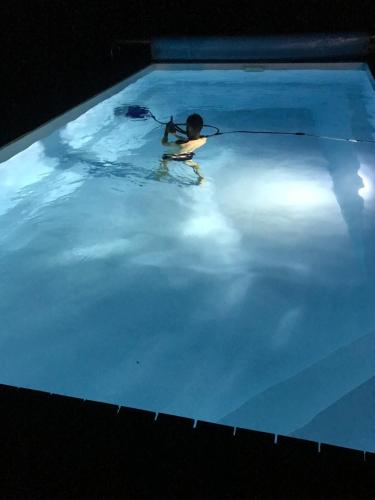 een persoon in een zwembad 's nachts bij Maison Golfe du Morbihan in Saint-Nolff