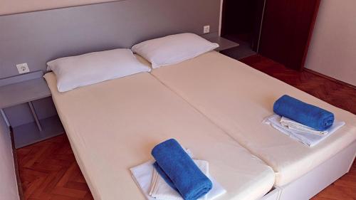 a large white bed with two blue pillows on it at Pansion Palme in Drvenik