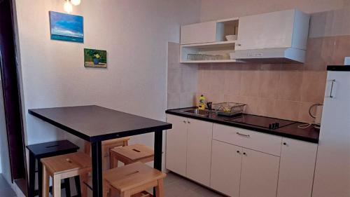 eine Küche mit einer Theke, einem Tisch und einem Kühlschrank in der Unterkunft Pansion Palme in Drvenik