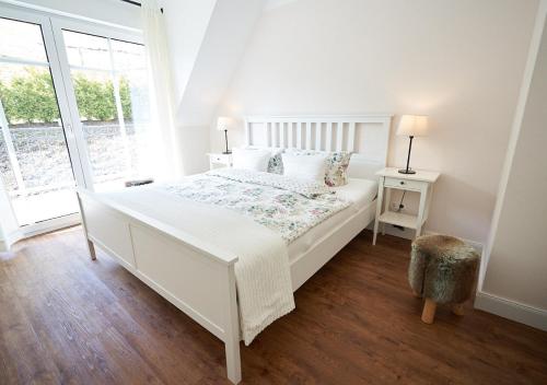 a white bedroom with a white bed and a window at Kleine Villa in Elpe