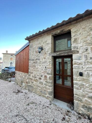 a stone building with a wooden door on it at Villetta Vittoria -Country House-Il fienile in Pennabilli