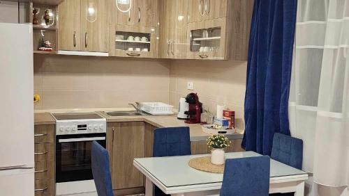 a small kitchen with a table and blue chairs at Apartman Rubikon in Kumanovo