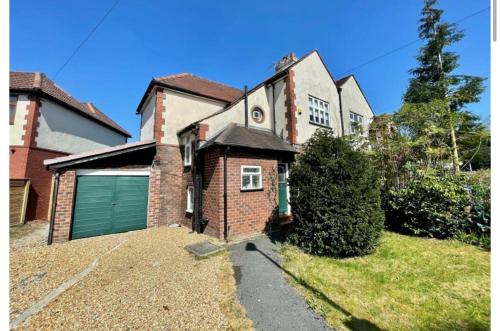 a large brick house with a green garage at Didsbury GEM ! FREE ONSITE PARKING ! STYLISH & CENTRAL in Manchester
