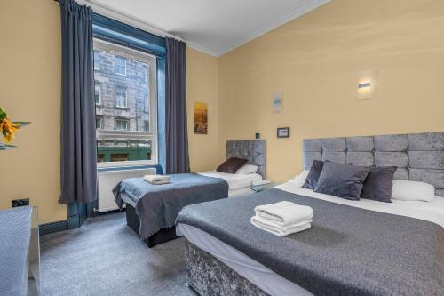 a hotel room with two beds and a window at Cosy modern city centre flat in Edinburgh