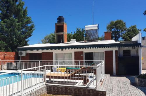 una casa de ladrillo con piscina frente a ella en Cabaña El Hornero en Mina Clavero