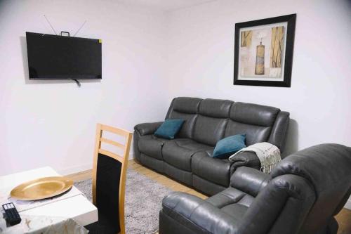 - un salon avec un canapé en cuir et une télévision dans l'établissement 6 bedroom property, à Sidcup