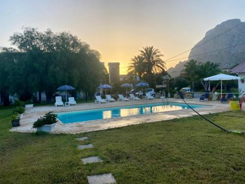 a pool with chairs and umbrellas in a yard at Villa Piruzzu CV Torre Mulinazzo app P in Cinisi