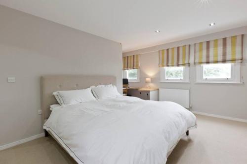 1 dormitorio blanco con 1 cama grande y 2 ventanas en Modern Town house in Barnes, West London, en Londres