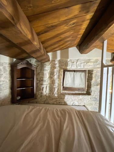 Cama en habitación con techo de madera en Villetta Vittoria -Country House-Il fienile en Pennabilli