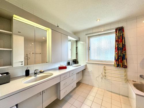 a bathroom with two sinks and a large window at Ferienhaus 80er Liebe mit Whirlpool in Lustenau