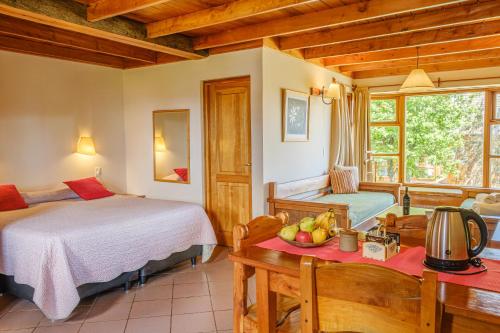 Un dormitorio con una cama y una mesa con un bol de fruta en Apart Hotel Del Arroyo en San Carlos de Bariloche