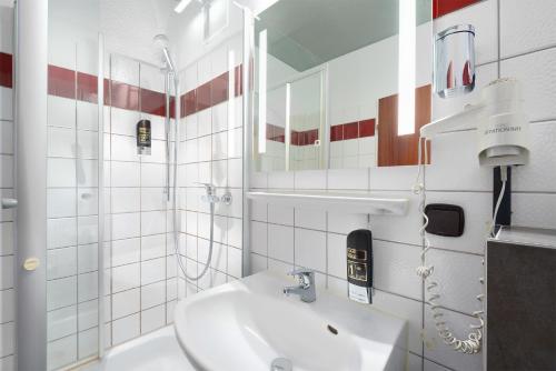 Baño blanco con lavabo y espejo en Trip Inn Hotel Krefeld, en Krefeld