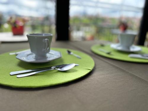 估納的住宿－Pitaya Suítes，两个绿盘,桌子上放有杯子和勺子