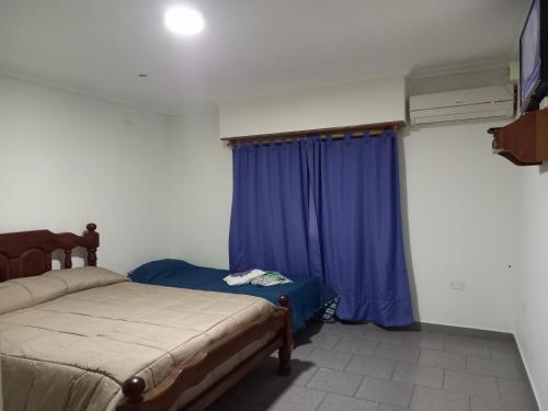 聖羅莎的住宿－Tesoro Escondido，一间卧室配有床和蓝色窗帘
