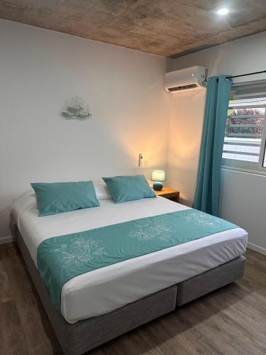 1 dormitorio con 1 cama grande con almohadas azules en Pension Irivai appartement "Uparu" 1 chambre bord de mer, en Uturoa