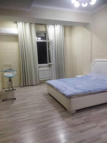 1 dormitorio con cama, mesa y ventana en apart NUR, en Bishkek