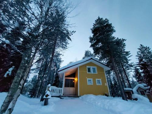 uma pequena casa amarela na neve na floresta em Lapland Forest Lodge em Rovaniemi