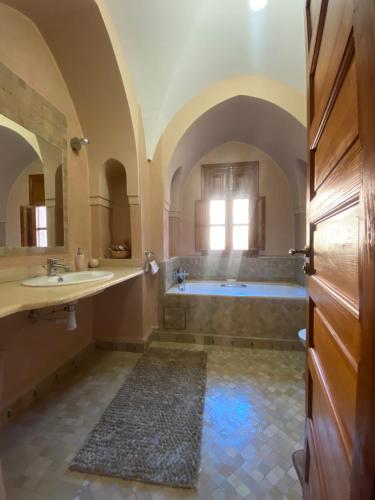 La salle de bains est pourvue d'une baignoire, de 2 lavabos et d'un miroir. dans l'établissement Villa les oliviers, à Marrakech