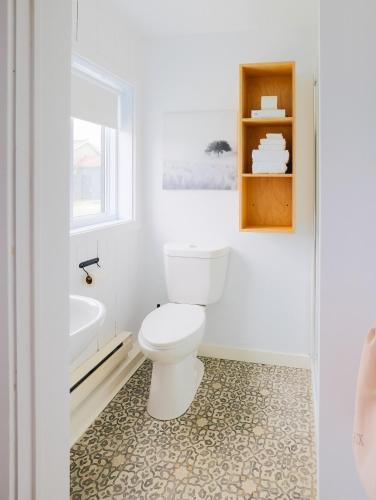 a white bathroom with a toilet and a sink at Beatnik Hotel in Bromont