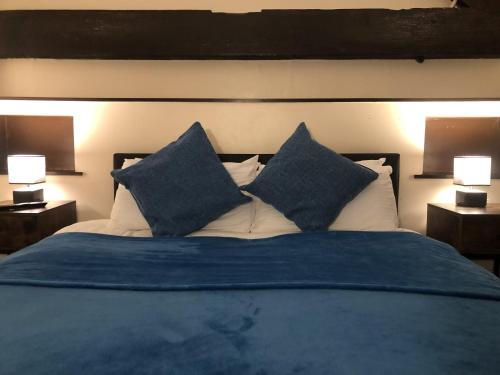 a bed with blue sheets and pillows with two lamps at The Old Bath Arms in Frome