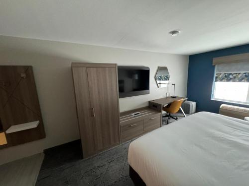 a hotel room with a bed and a flat screen tv at Holiday Inn Express & Suites Port Washington by IHG in Port Washington
