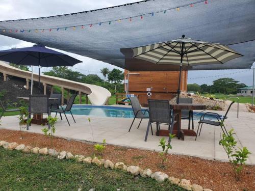 un patio con sombrillas, una mesa y sillas junto a una piscina en Sanctuary at Paslow Falls-Belize, en Bullet Tree Falls