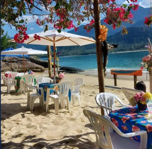 Casa praias de São Gonçalo em Paraty RJ في باراتي: مجموعة من الطاولات والكراسي على شاطئ رملي
