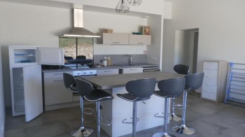 - une cuisine avec une table et des tabourets de bar dans l'établissement Maison au cœur de la vallée du DOUX , Ardeche, à Colombier-le-Vieux