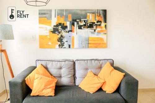 Departamento Calle 70 في لا بلاتا: أريكة رمادية مع وسائد برتقالية في غرفة المعيشة