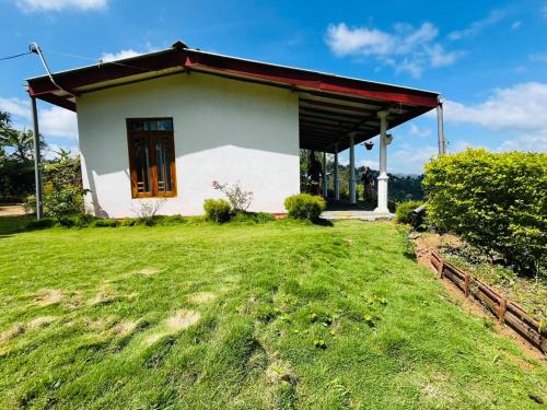 a small white house with a grass yard at Ella Black Bridge View Cottage Sri Lanka in Ella