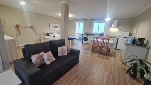 a living room with a black couch and a kitchen at Villa Alta Vista in São Jorge