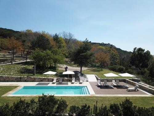a swimming pool with chairs and umbrellas in a yard at Gerês - Leiras do Tempo - Suite Alecrim in Terras de Bouro