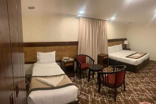 a hotel room with two beds and a table at Hotel Abdelmalek Al Azizia in Makkah