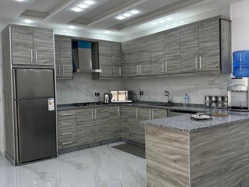 a kitchen with wooden cabinets and a stainless steel refrigerator at AL-TARAF FARM in Umm el ‘Amad