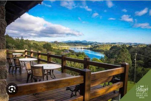 una terraza con mesas y sillas y vistas al río. en Apto Eco Resort Capivari - CTBA, en Campina Grande do Sul