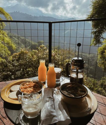 a table with food and orange juice and a view at Paneo Glamping in Floridablanca