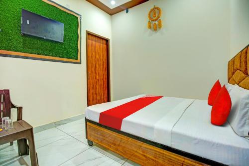 Schlafzimmer mit einem Bett mit roten Kissen und einem TV in der Unterkunft OYO Hotel Patiala in Kurukshetra