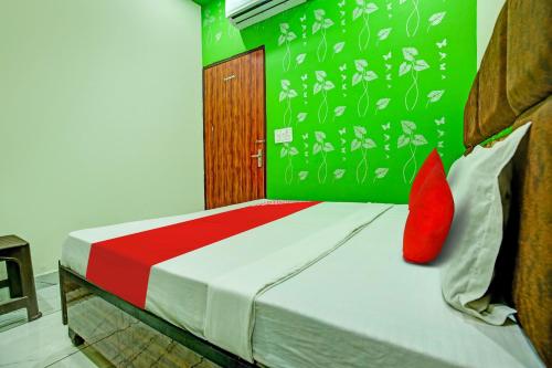 a bedroom with a bed with red pillows and a green wall at OYO Hotel Patiala in Kurukshetra