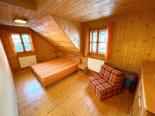 a bedroom with a bed and a chair in a room at Chalupa pod lipou in Zázrivá